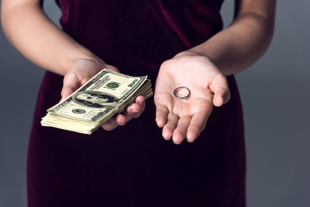 Woman with a wedding ring in one hand and money in the other