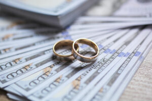 two golden wedding rings laying on dollars