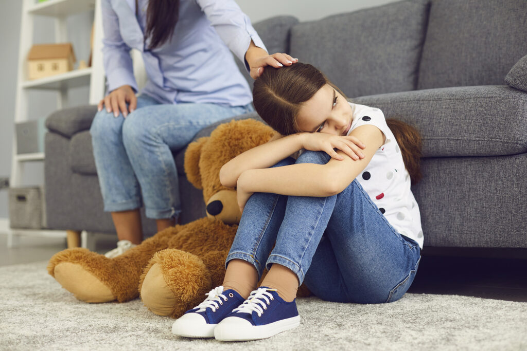 daughter sitting on floor while mom touches her head